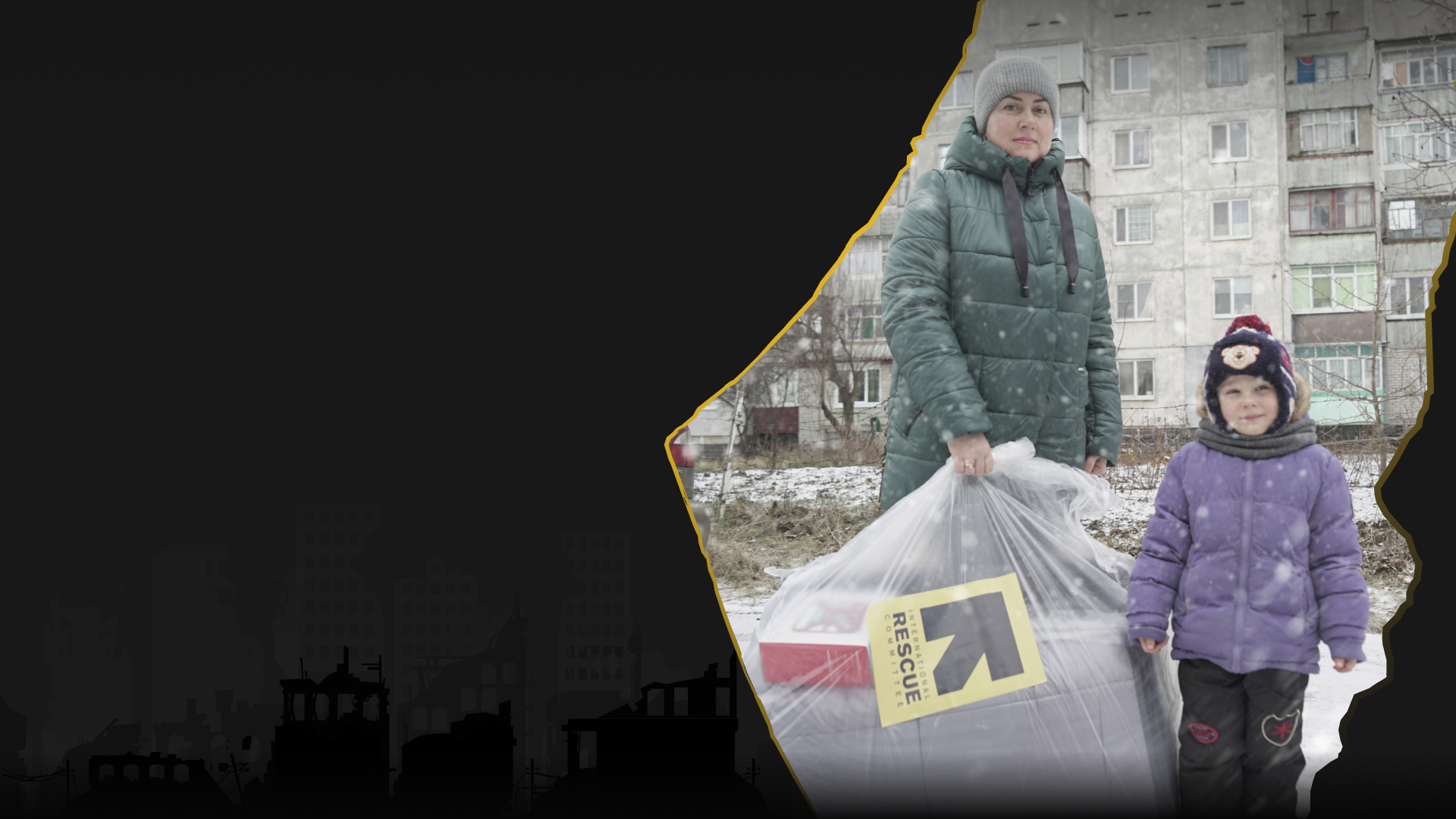 눈 내리는 날, 구호 물품을 받은 보호자와 아이가 서 있는 모습